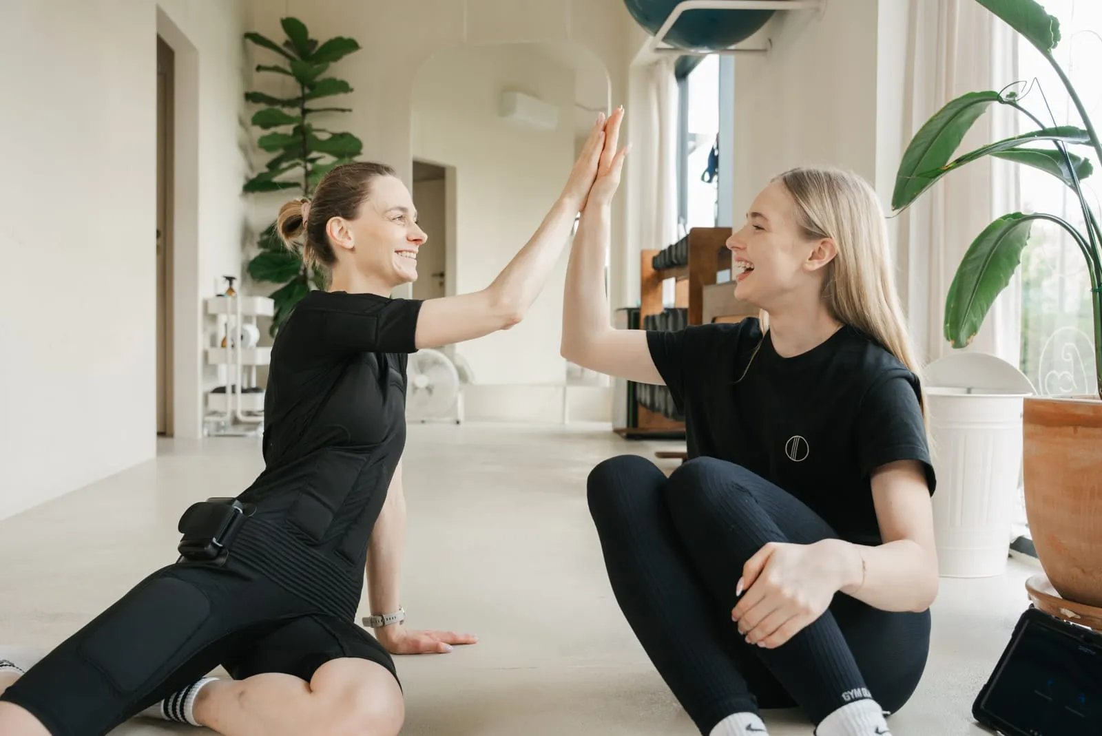 Klientka w stroju EMS i trenerka przybijają piątkę po treningu