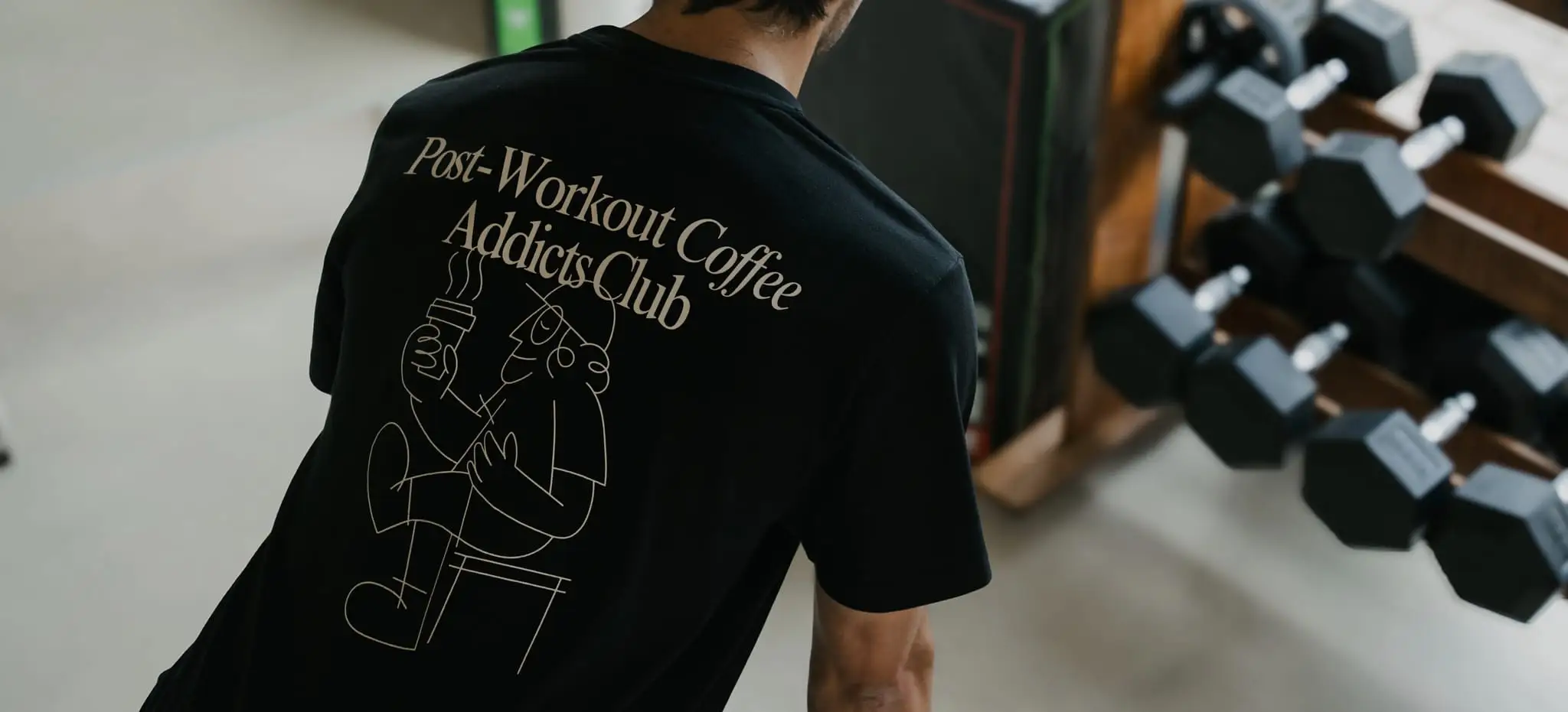 Zbliżenie na nadruk „Post-Workout Coffee Addicts Club” na plecach czarnego T-shirtu WORK IT